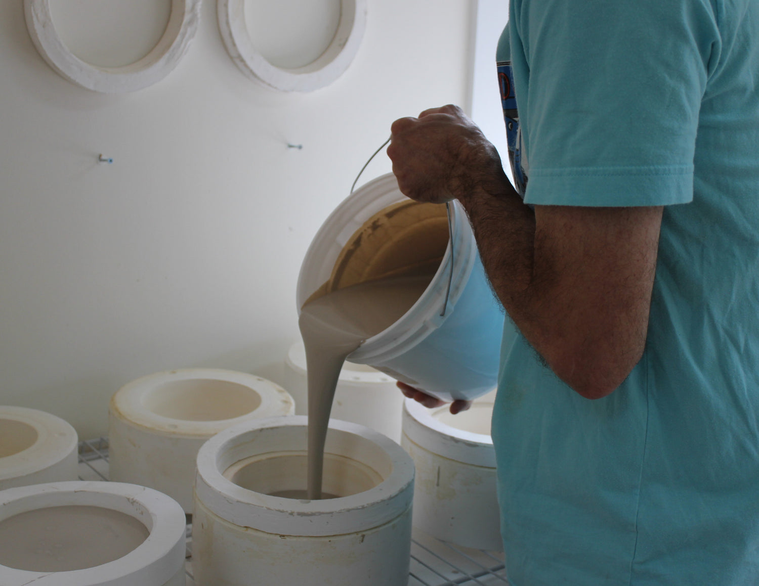 Stoneware liquid slip being poured into a casting mold for a dog bowl.
