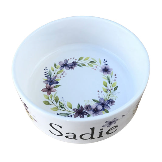 White personalized dog bowl with image of circular purple flower border in center of bowl. 